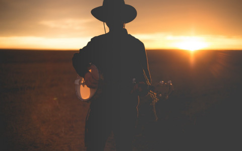 man playing banjo during the sunset outside