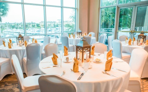 Ballroom setup for wedding with white table cloths and yellow accented napkins