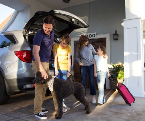 family unloading luggage from car