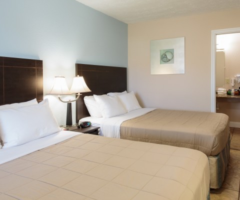 Room with two beds, nightstand and bathroom