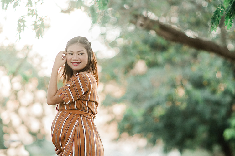 young pregnant lady looking to the right side while she is touching her hair in the nature