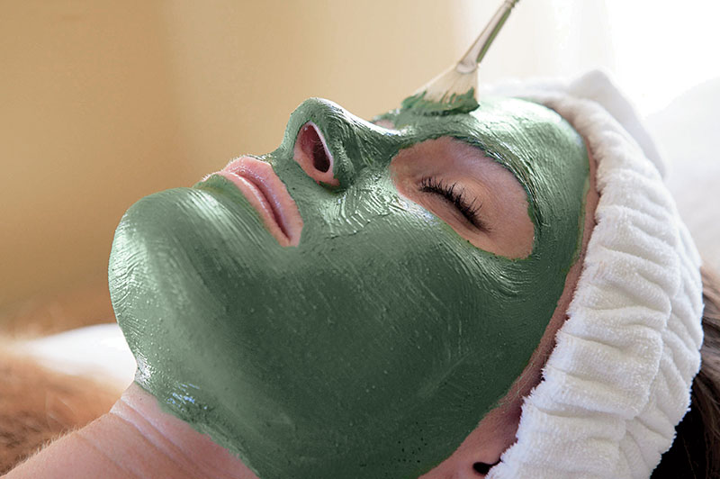a woman receiving a green mud facial