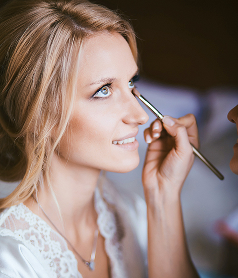 a bride getting her makeup done on her wedding day