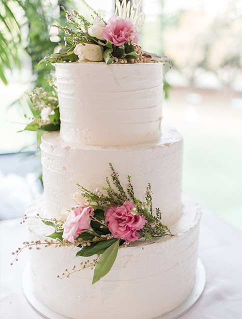 view of a white 3 tier wedding cake with pink flowers