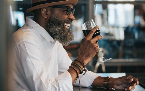 guy smiling and enjoying a red glass of wine at the bar