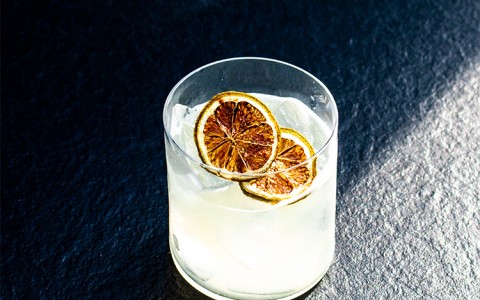freshly made cocktail topped with two slices of torched oranges