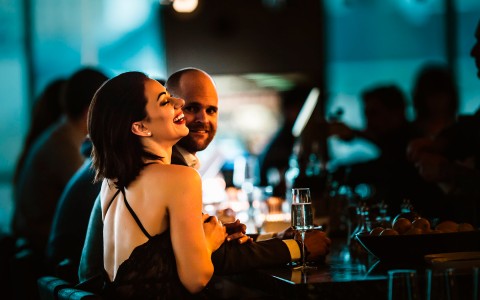 couple sitting at the bar and the lady laughing as she has her arms wrapped around his