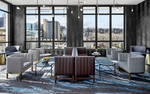modern lounge with sleek lights hanging over the seats and large windows with a view of the city
