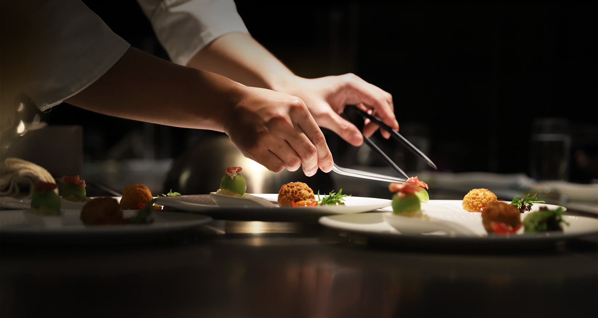the chef carefully placing the garnish on top of the dishes with professional tools