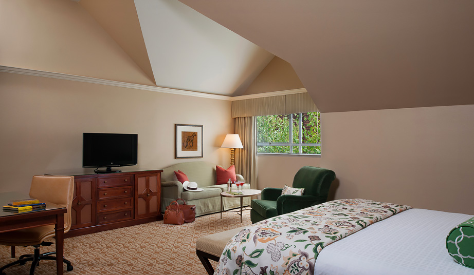 large room with bed facing tv and dresser with light green sofa large room with bed facing tv and dresser with light green sofa