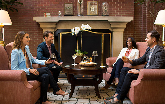4 people sitting around a coffee table in front of a fireplace