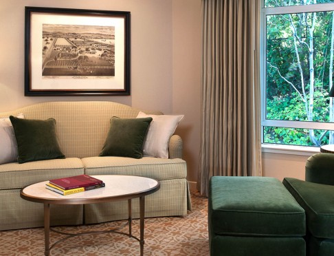 Guest room sitting area with green striped sofa and green chair by window