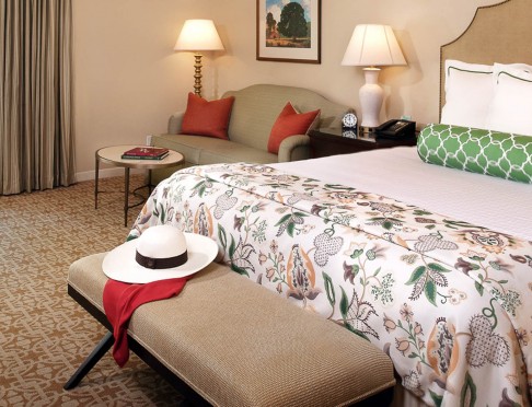 Queen Bed with floral duvet, green pillow and bench at the foot of the bed