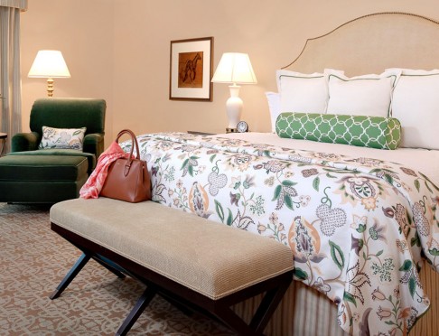 King bed with white and floral bedding and bench at foot of the bed
