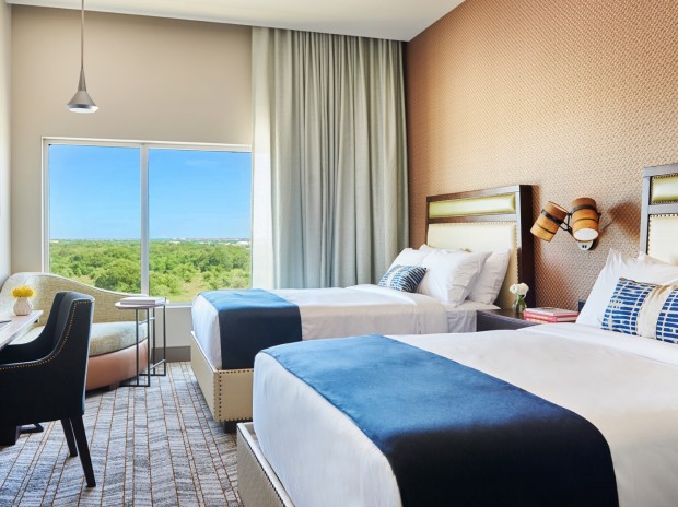 deluxe double queen room with two beds, desk and chair and lounge chair