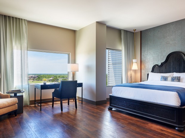 room with a king bed, desk and chair, lounge chair, window
