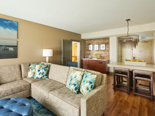 living room area with couch, tables and bar in background