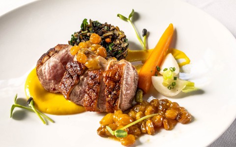 steak entree with colorful garnishes on a white plate 