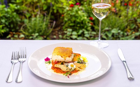 seafood dish served in a white plate accompanied by a glass of white wine