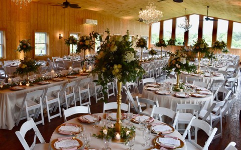 Wedding venue decorated with a long table as well as round tables with tall center pieces