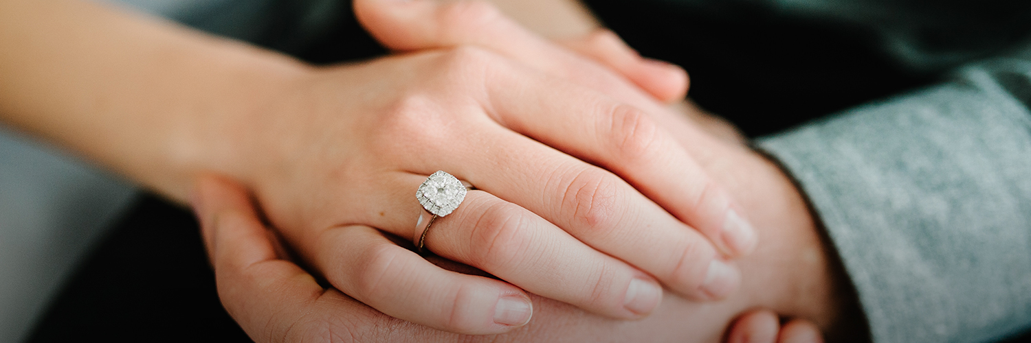 above close up photo of the bride hand with her marriage ring on and holding the groom hands
