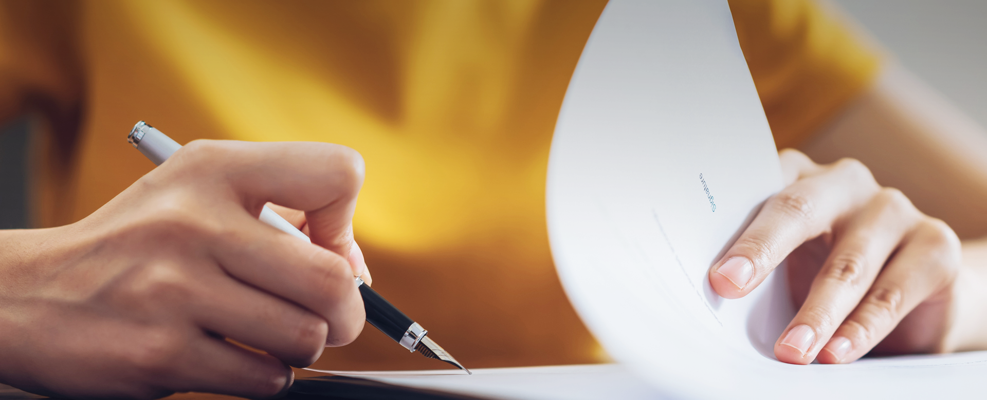 womans hands signing papers