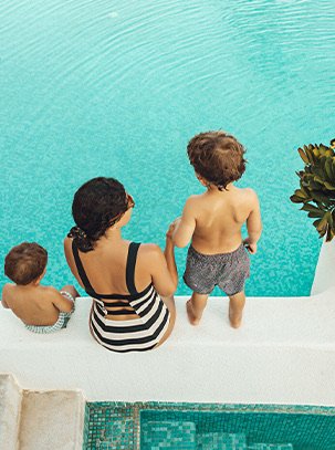 A woman with two kids sitting next to the pool.