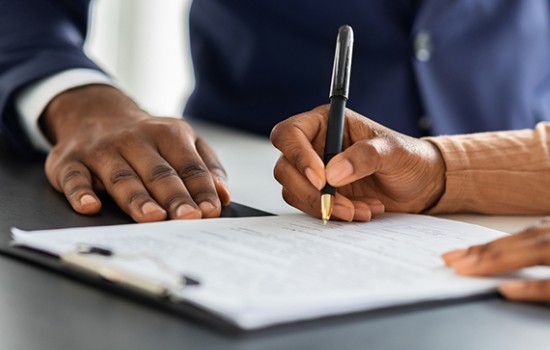 A woman signing a document wit a man next to her.