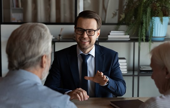 A smiling businessman talking to a couple.