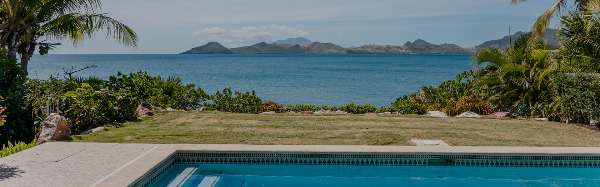 The blue ocean and mountains next to the land.