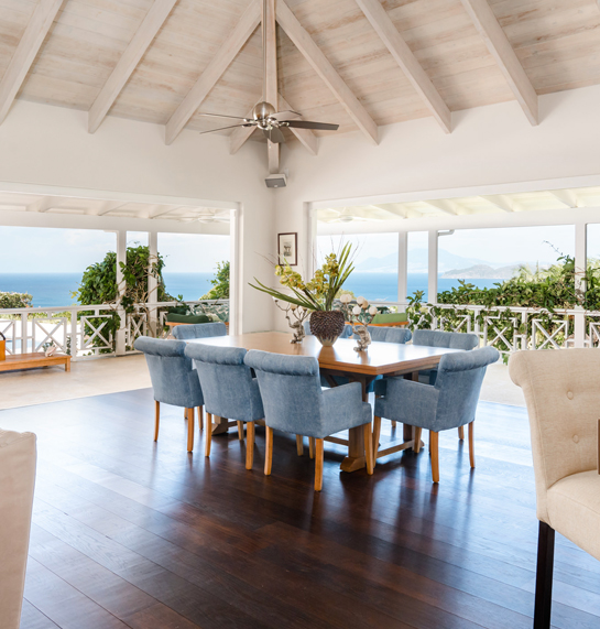 Open air dining room with tall ceilings and a view of the ocean on both sides.