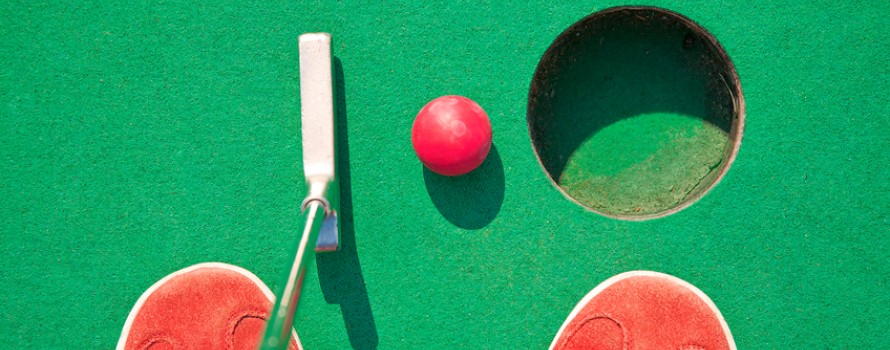 red Miniature golf club and ball on green