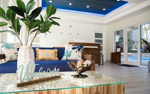 entrance of the hotel with beach decor and a couch in front of the receptionist desk