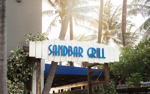sandbar grill sign with palm trees in the back