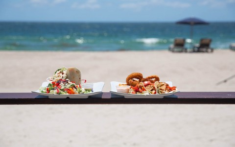 two taco plates on the table in front of the beach