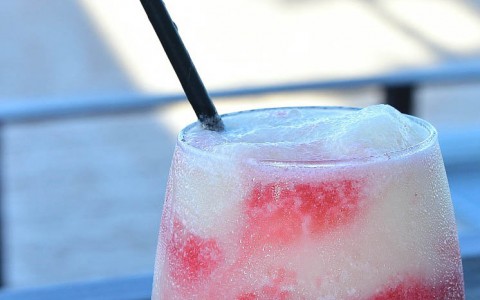 frozen margarita on the table with the beach in the background