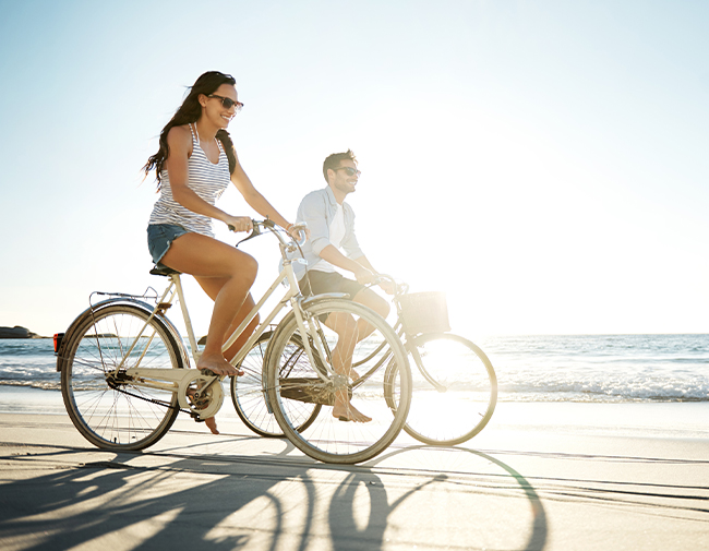 man and woman riding bikes along the beach