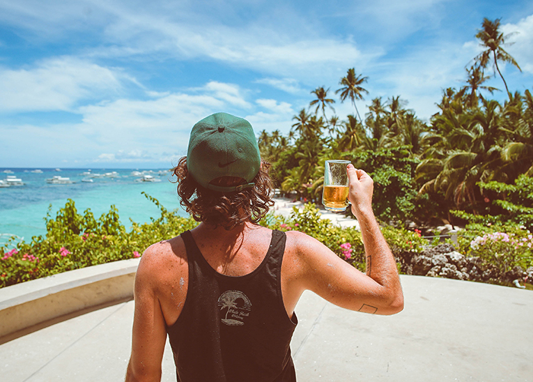 guy looking towards the beach while holding up a beer