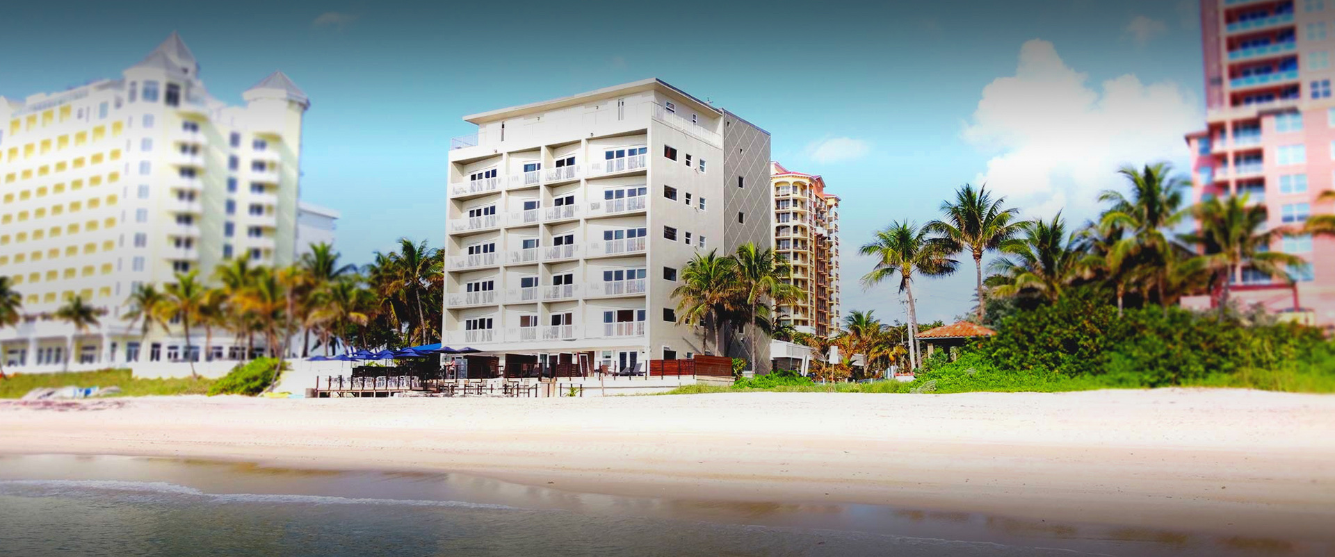 hotel building in front of the ocean with palm trees around