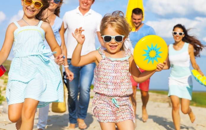 family running along the beach with beach toys