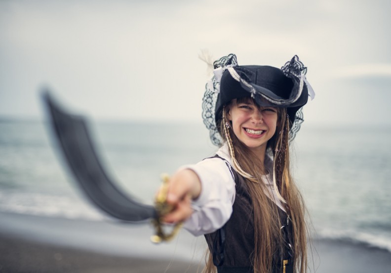 girl dressed as pirate on beach
