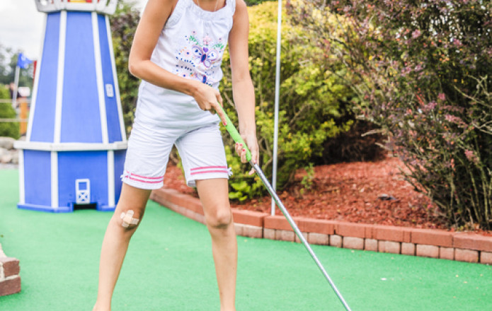 little girl play mini golf