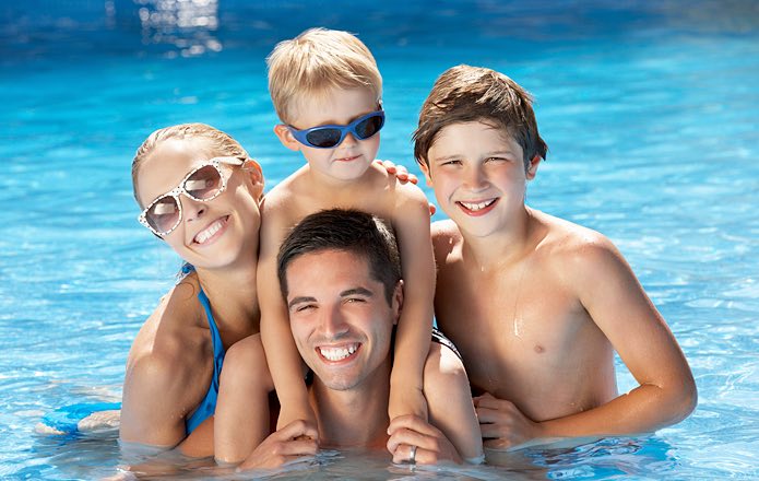Four people in a pool in the sun