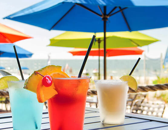 multicolored tropical drinks sitting on a table under umbrella