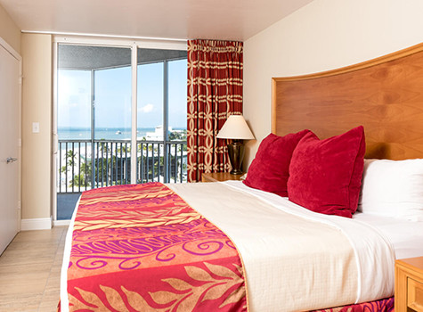bedspread with a red and purple color and red pillows overlooking ocean