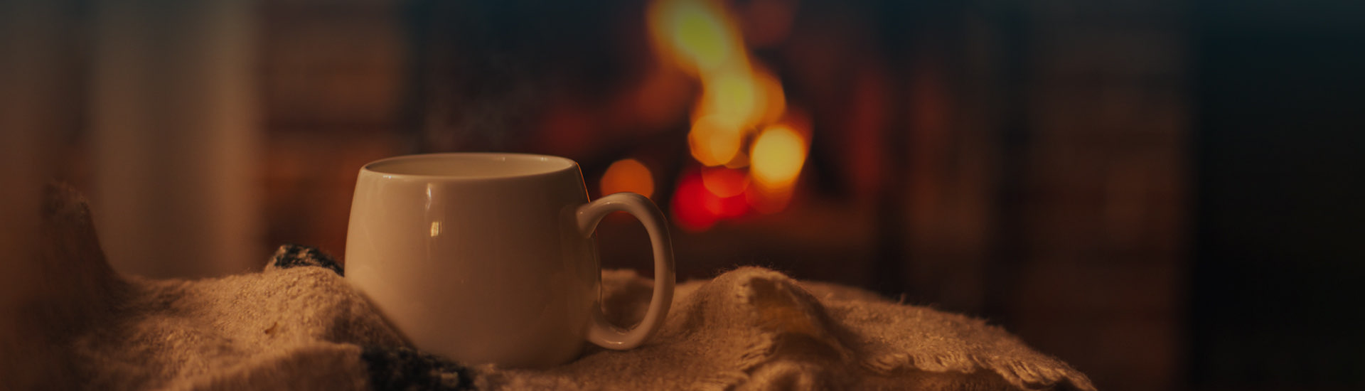 close up view of coffee cup with fireplace in the background hero
