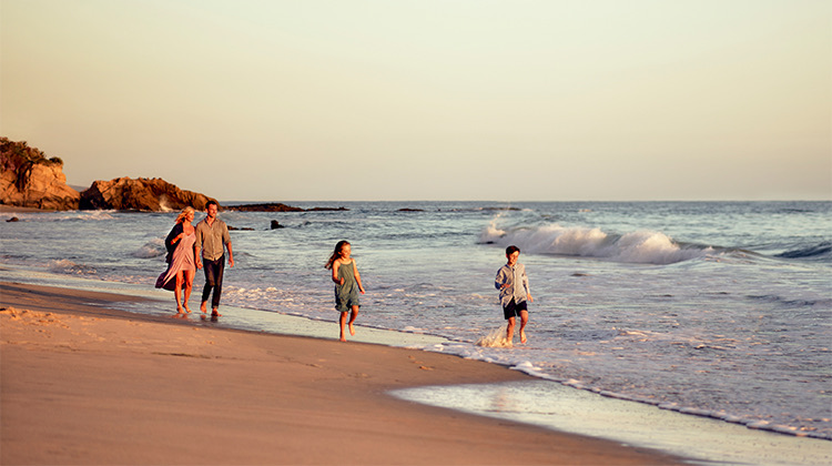 family of four walking and running on the beach