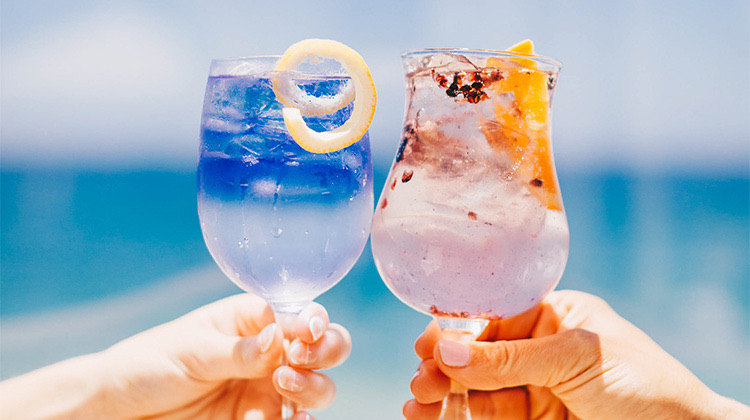 close up of two fancy and colorful cocktails clinking