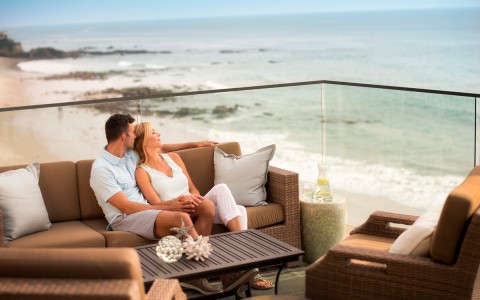 a couple sitting on a couch looking at the ocean