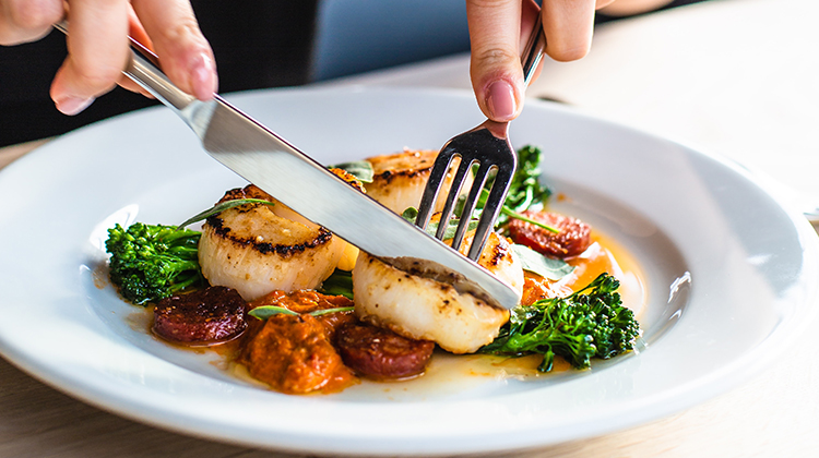 an individual cutting into their elegant entree
